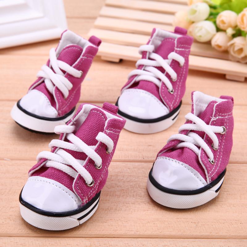 pink denim dog sneakers with white laces on wood table